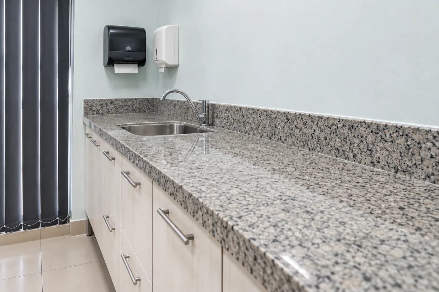 Bancada de granito com pia e dispensers de papel e sabonete em consultório da Prodentex